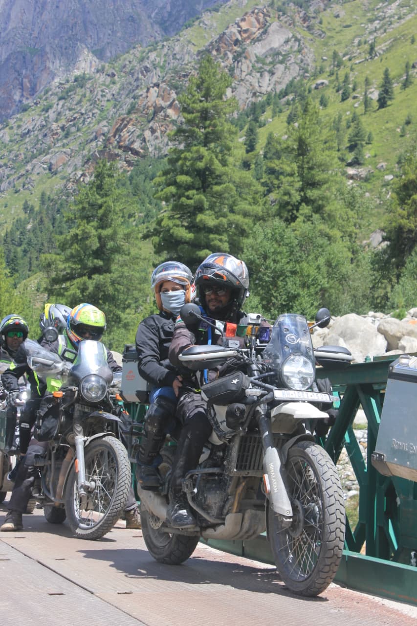 Riders crossing a forested bridge in Kinnaur